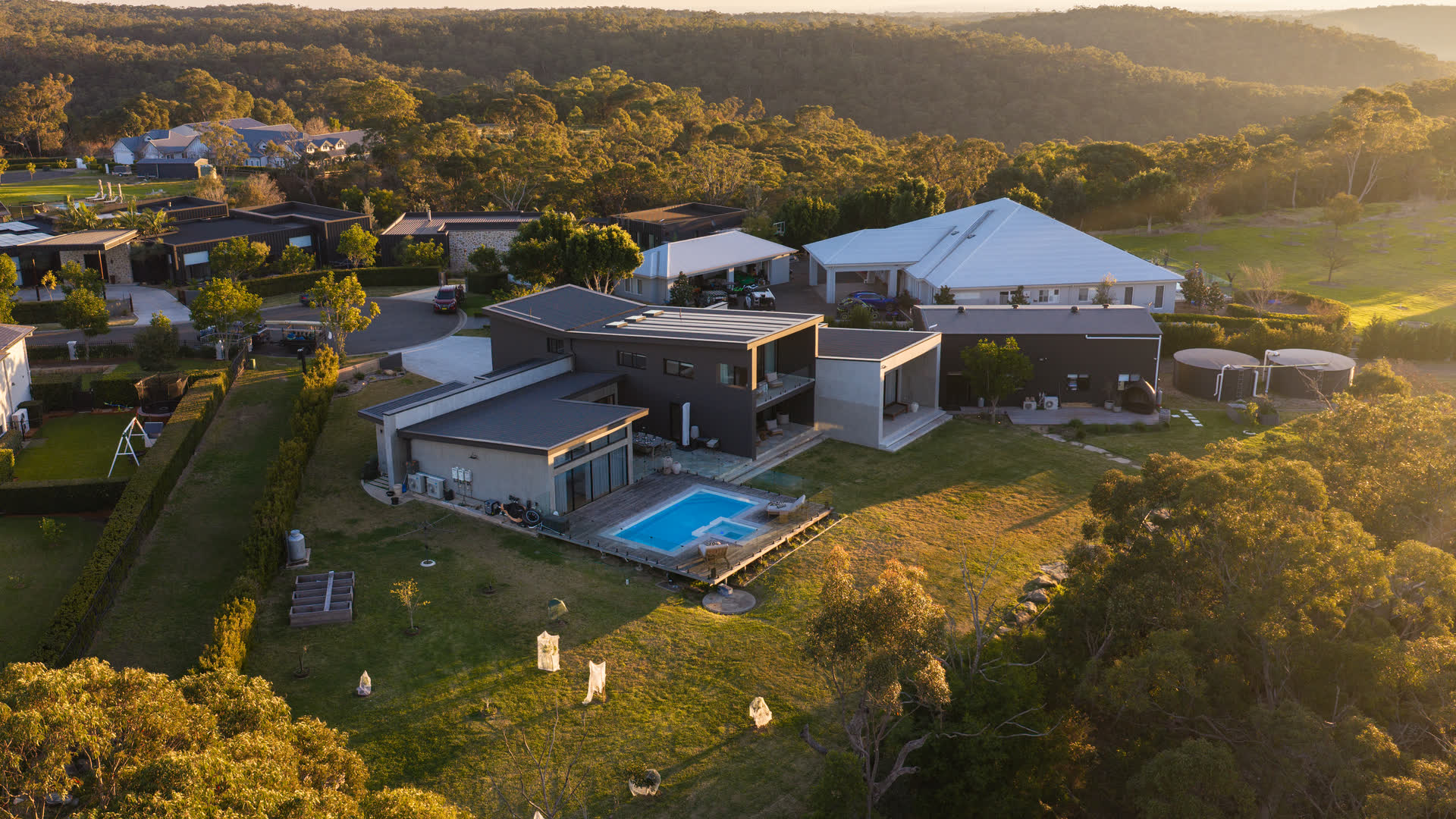 Aerial view at sunset of a completed LetsBuild house at Glenorie, with pool, deck and bushland behind