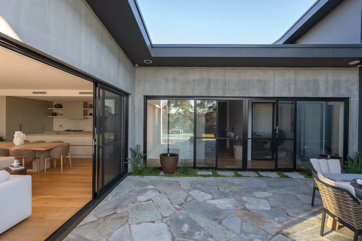 The internal courtyard at Glenorie seen through the void — off-form concrete, glass and flagstone under open sky