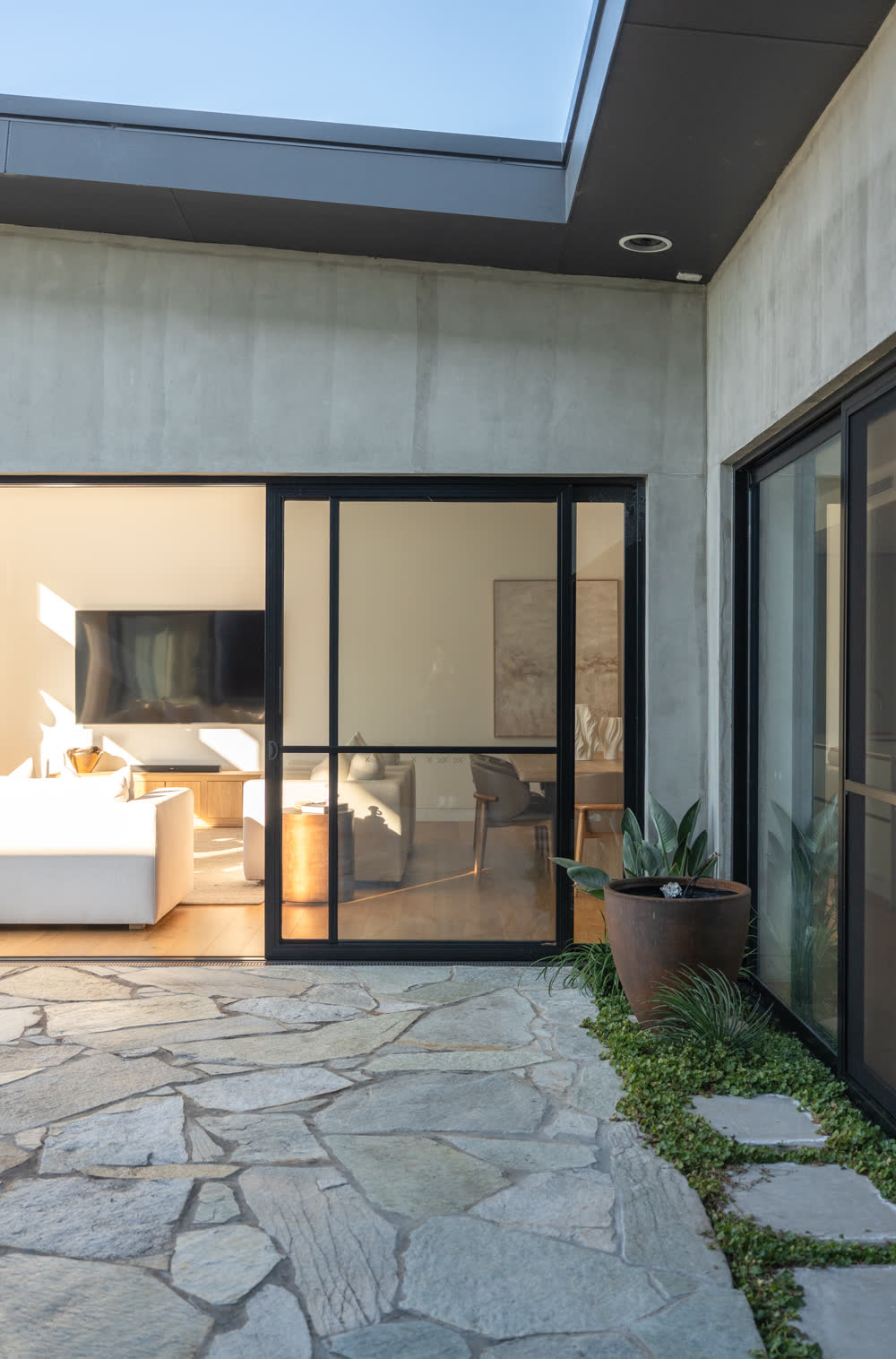 Internal courtyard at Glenorie — flagstone floor and garden bed wrapped by the concrete and glass of the house