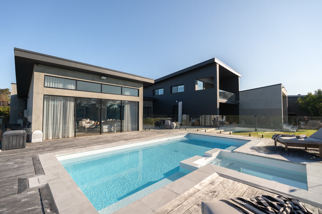 The completed Glenorie project — pool and spa wrapped by the pavilion and main house at golden hour