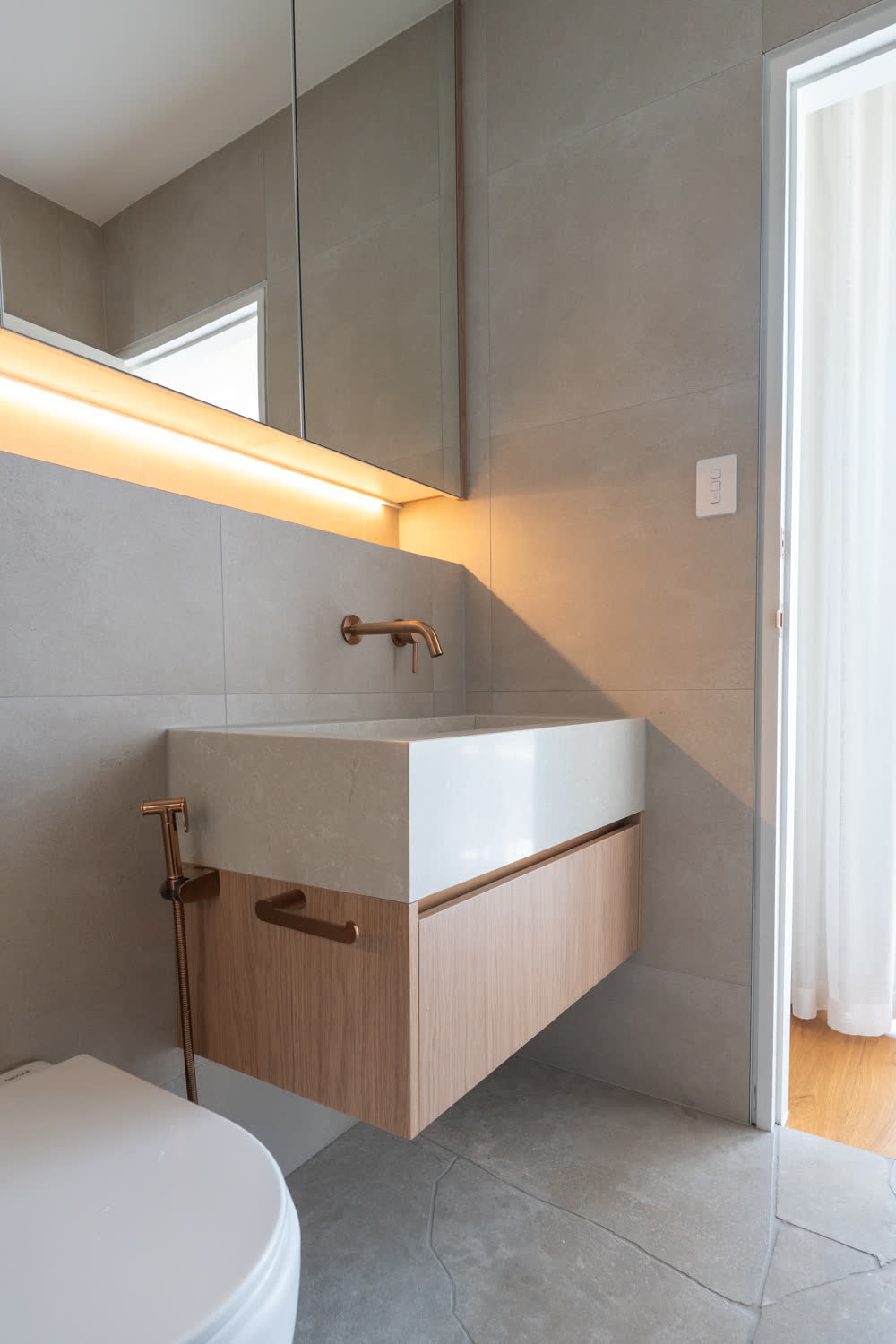 Powder room at Glenorie — carved stone trough basin with wall-mounted brass mixer under a lit mirror shelf